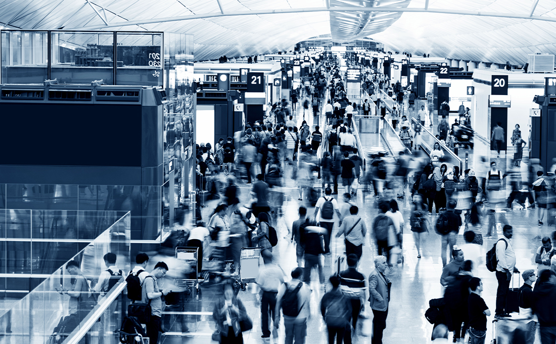 Black and white photo of a crowd of people walking through a conference hallway