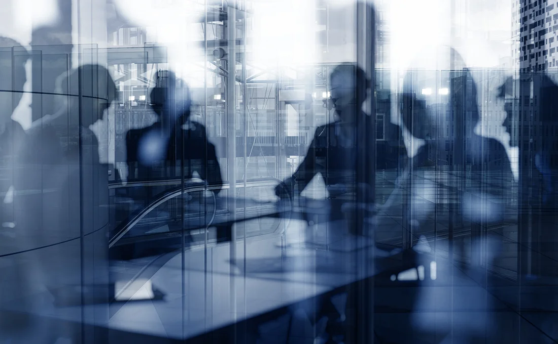 Blurry image of a group of people at a conference table having a meeting